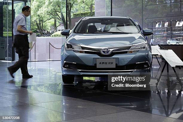 Man walks past a Toyota Motor Corp. Corolla hybrid vehicle displayed at the company's head office in Tokyo, Japan, on Wednesday, May 11, 2016. Toyota...