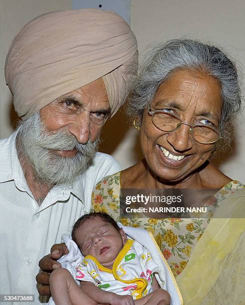 Indian father Mohinder Singh Gill and his wife Daljinder Kaur pose for a photograph as they hold their newborn baby boy Arman at their home in...