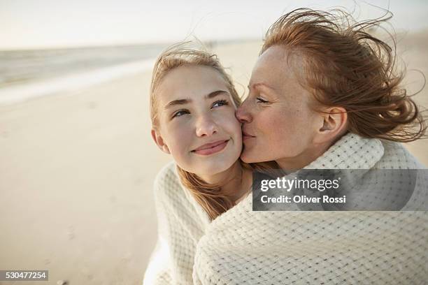 mother kissing daughter on the beach - mother and daughter kissing stock pictures, royalty-free photos & images