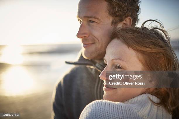 happy couple on the beach - mid adult couple stockfoto's en -beelden