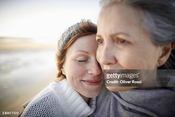 mother and adult daughter on beach - daughter stock-fotos und bilder