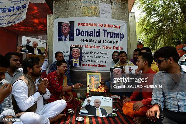 An Indian Hindu priest performs a Hawan ritual alongside posters bearing the image of US Republican presidential candidate Donald Trump in New Delhi...