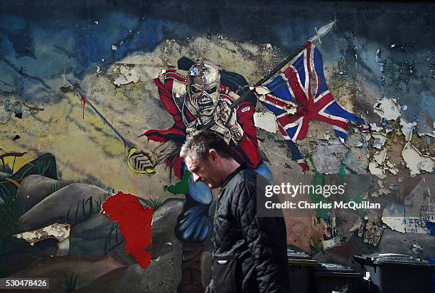 Man walks past a mural marking unionist territory on May 4, 2016 in Londonderry, Northern Ireland. The city of Londonderry is situated on the border...