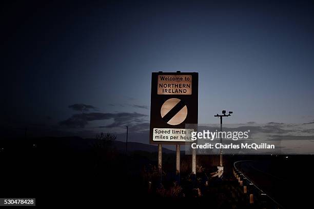 Welcome to Northern Ireland road sign indicating the change from kilometers per hour to miles per hour speed laws is illuminated by car headlights on...
