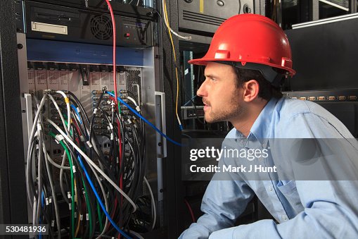 Network engineer examining system configuration at patch panel Network engineer examining system configuration at patch panel