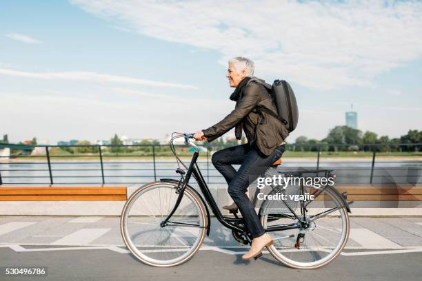 mature woman riding bicycle. - business woman side stockfoto's en -beelden