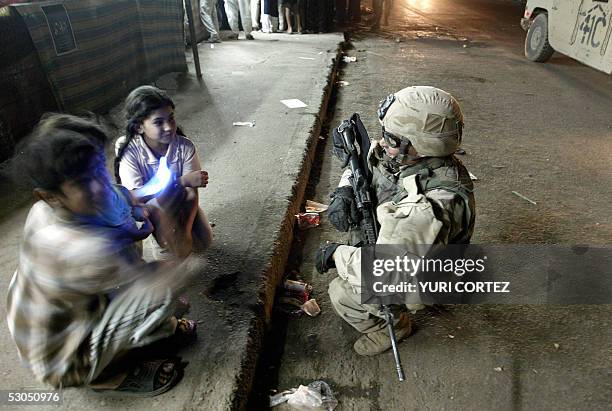 Soldier, Jesse McNaughton from Ohio, of the Charlie Company 3rd BN 7th Infantry chats with two children in a neighbourhood in southern Baghdad, in...