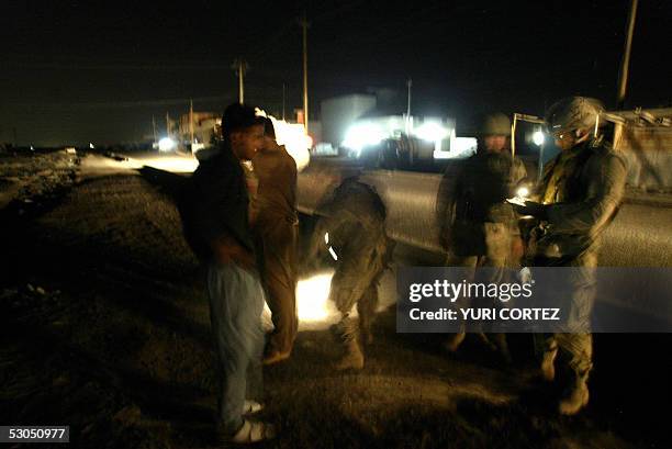 Soldiers of the Charlie Company 3rd BN 7th Infantry check the documents of two Iraqi boys in the streets of neighbourhood in southern Baghdad, in the...