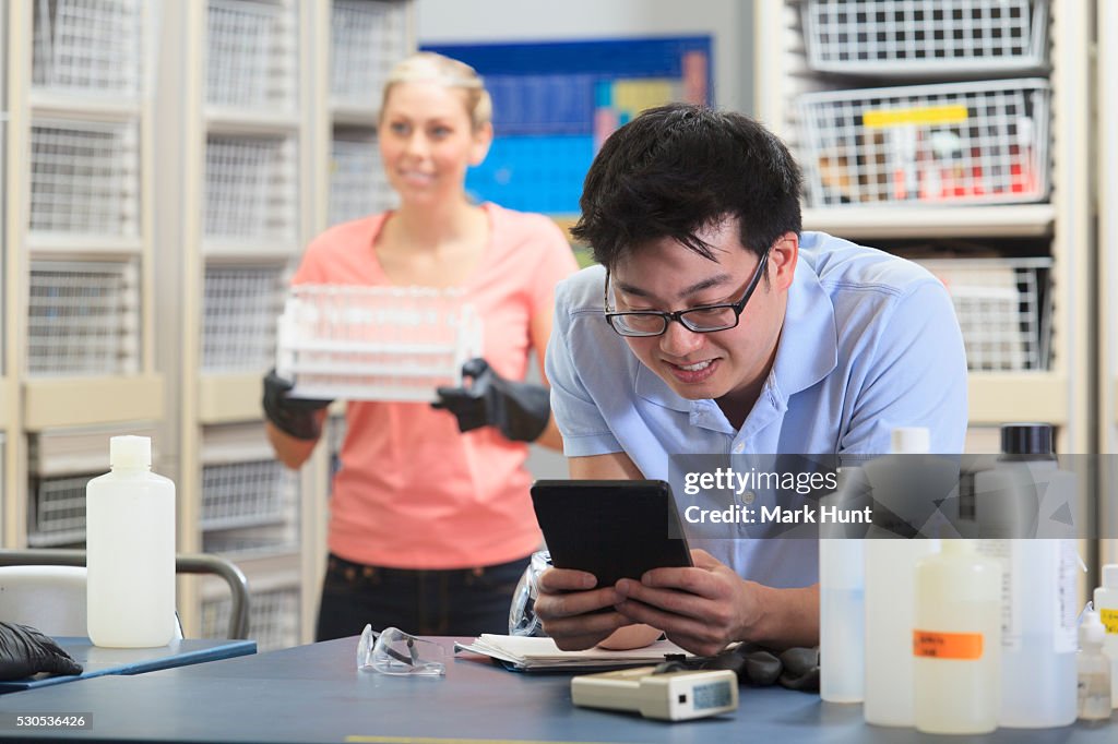 Engineering student using a tablet to record data in chemistry laboratory