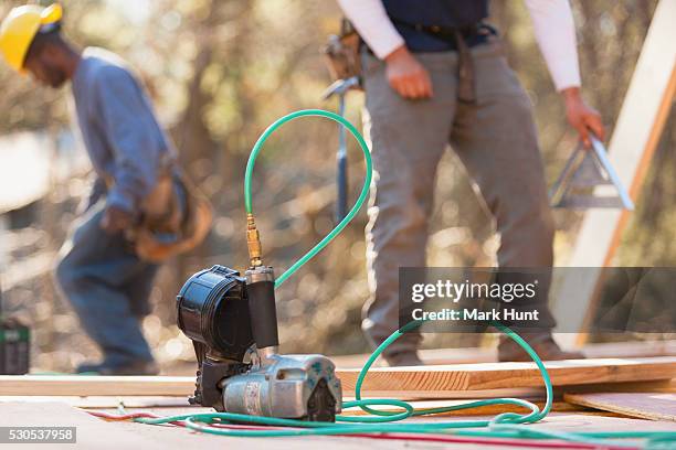 carpenters with a nail gun in the foreground - nail gun stock pictures, royalty-free photos & images