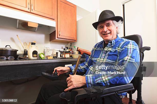 man with multiple sclerosis in a wheelchair sitting in his accessible kitchen - man fedora room stock pictures, royalty-free photos & images