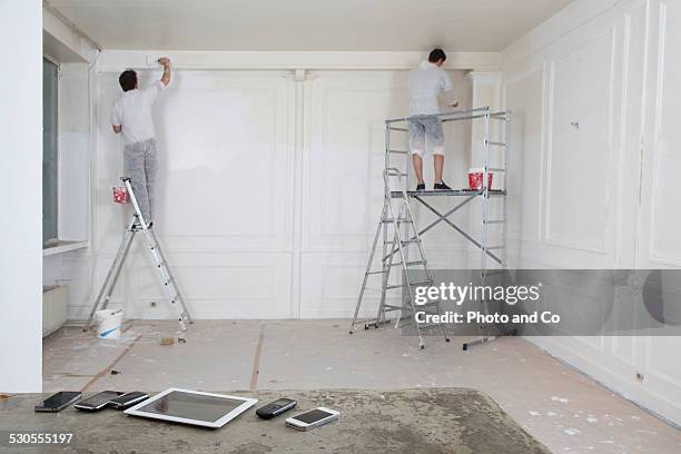 men painting a wall with tablet and phone - step ladder stock-fotos und bilder