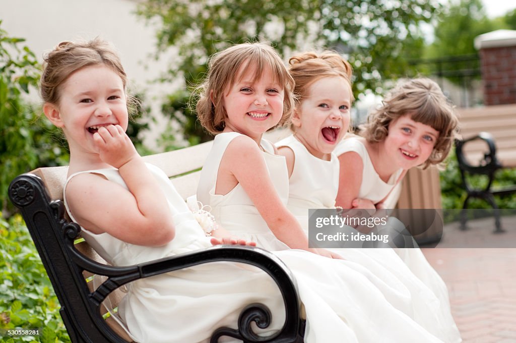 Vier glückliche kleine Blumenmädchen lachen zusammen in eleganter Kleider