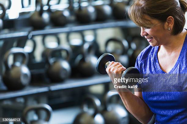 hispanic woman at gym lifting dumbbell - hand weight stock pictures, royalty-free photos & images