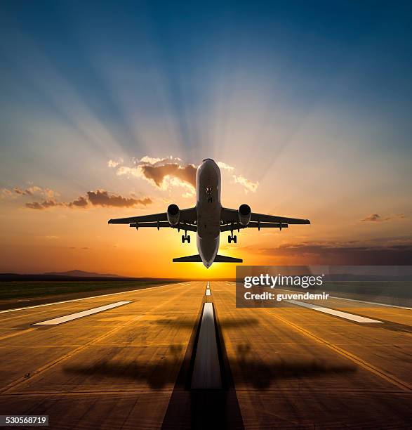 passenger airplane taking off at sunset - golden clouds stockfoto's en -beelden