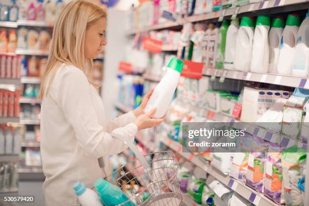 woman choosing fabric softener - wasmiddel stockfoto's en -beelden