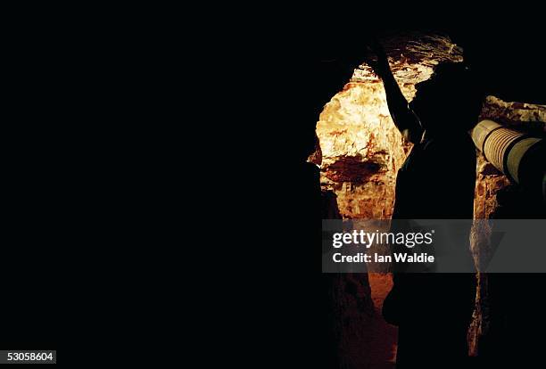 Opal miner John Shane inspects a rock face in his underground mine June 12, 2005 in the outback mining town of Coober Pedy, Australia. Australia...