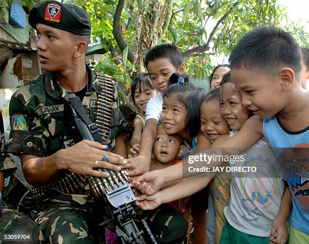 Young children touch with awe a soldier's loaded M-60 machine gun, 13 June 2005, as six truckloads of troops were dispatched to a Philippine Catholic...