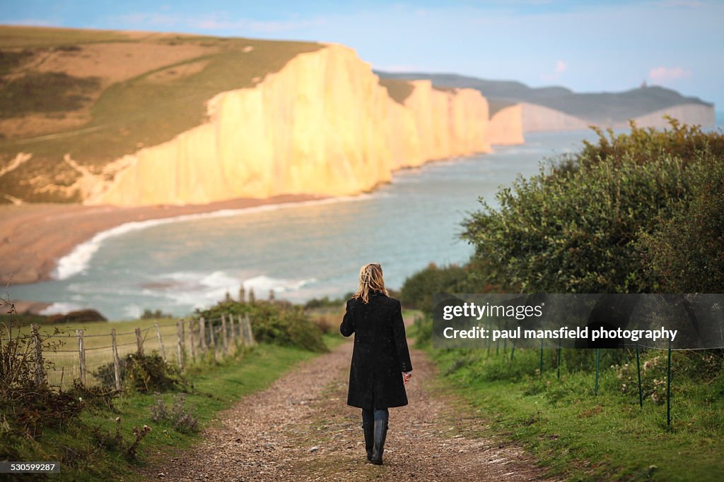 Lady walking towards cliff coastline