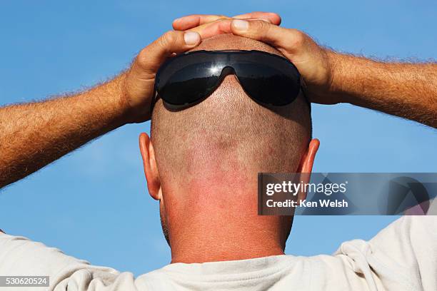 man wearing sun glasses on the back of his shaven head and with his hands resting on top of his head; spain - glasses on top of head stock pictures, royalty-free photos & images