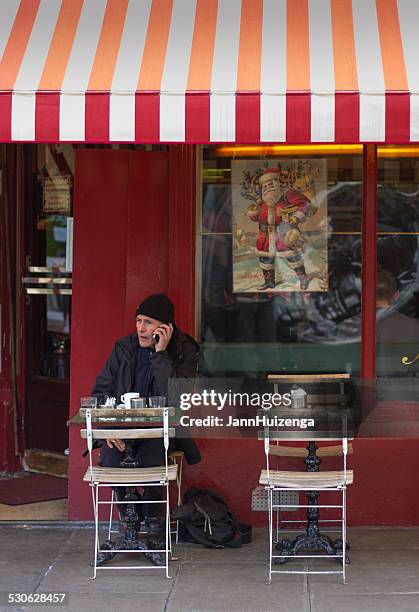 man chats on cell phone at dublin sidewalk cafe - striped awning stock pictures, royalty-free photos & images