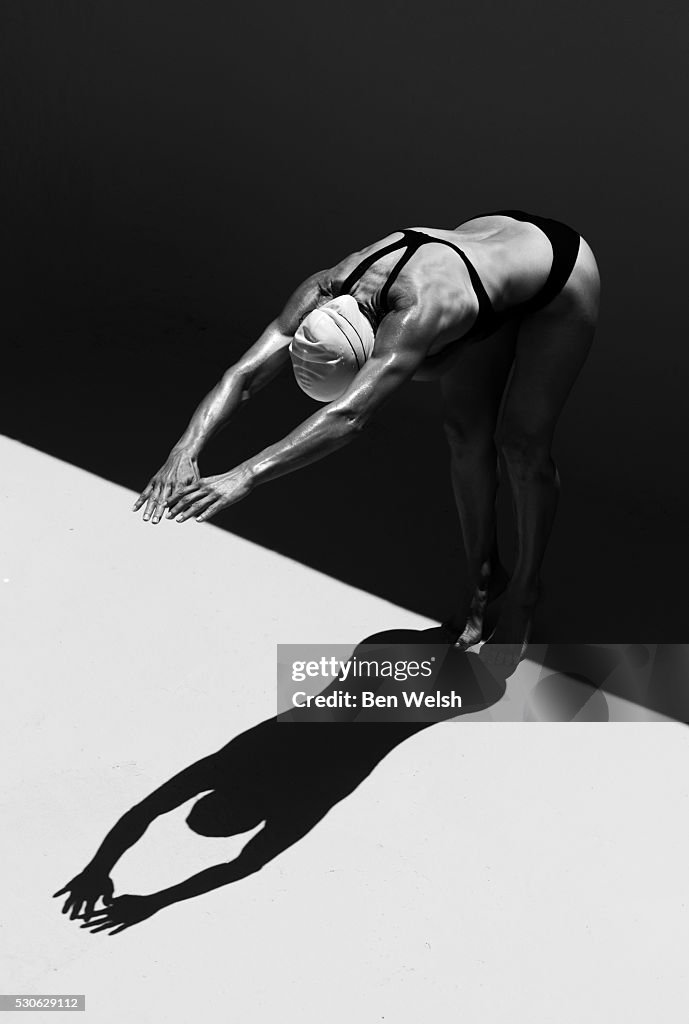 A Woman Prepares To Jump Backwards Off The Edge Of A Pool Into The Water; Tarifa, Cadiz, Andalusia, Spain