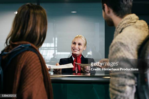 young traveller couple at check-in counter - airport crew stock pictures, royalty-free photos & images