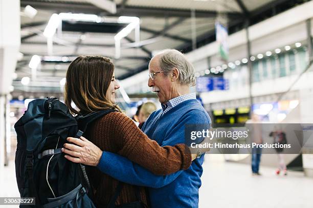 grandfather welcoming young traveller - umarmen stock-fotos und bilder