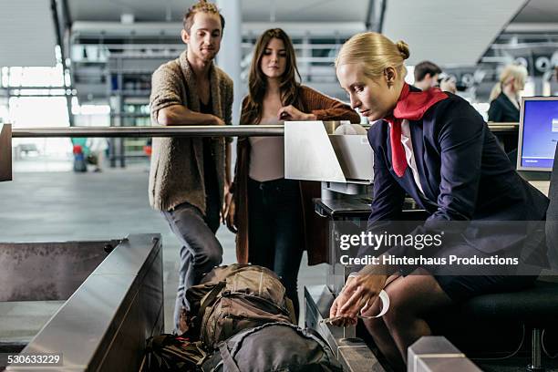 young couple at airport baggage drop off - luggage stock pictures, royalty-free photos & images