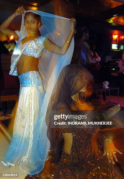 In this picture taken late 06 May 2005, Indian men watch as dancer Nikita and Rani perform a routine at a dance-bar in Mumbai. The western Indian...