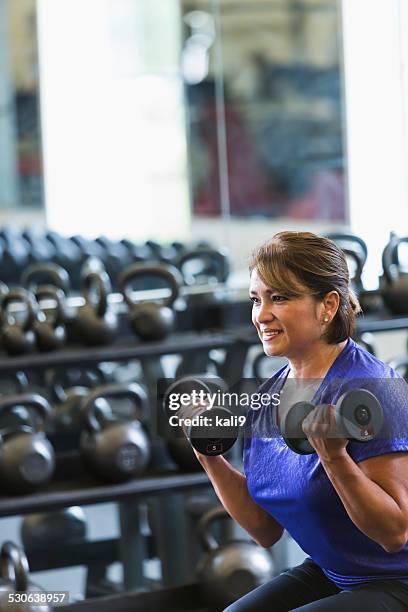 hispanic woman at gym lifting dumbbells - tyngdlyftning bildbanksfoton och bilder