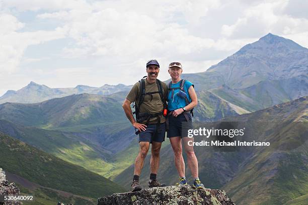 male and female hiker stand with a view over the landscape of mountains and valleys; yukon, canada - active baby boomer stock pictures, royalty-free photos & images