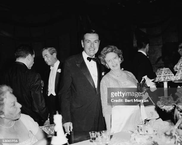 Canadian-born beautician and cosmetics entrepreneur Elizabeth Arden and John A Treat, both dressed in formal attire, stand together and smile for the...