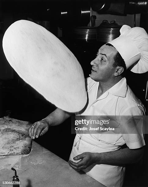 Vince Guiffire, owner and cook at Vince's Spaghetti House in Lake City, Seattle, tosses some pizza dough. 1959. | Location: Lake City, Seattle,...