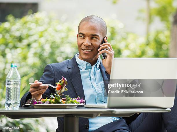 black businessman working and eating lunch outdoors - business lunch outside stock pictures, royalty-free photos & images