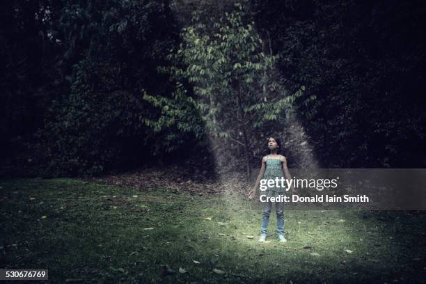 mixed race girl standing in beam of light outdoors - spotlight person stock pictures, royalty-free photos & images