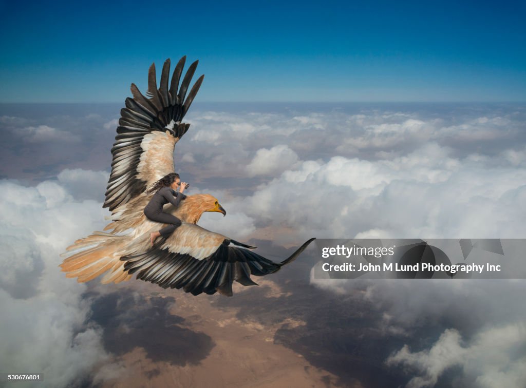 Woman riding eagle flying over clouds in sky