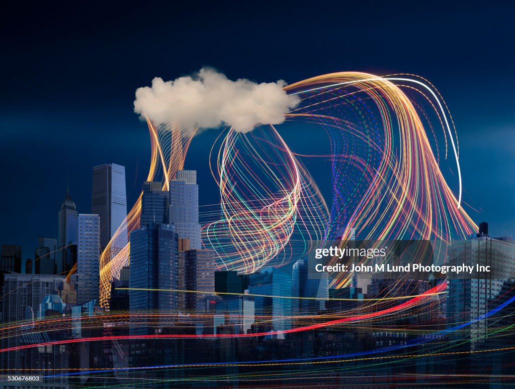 Illuminated light trails and cloud over cityscape