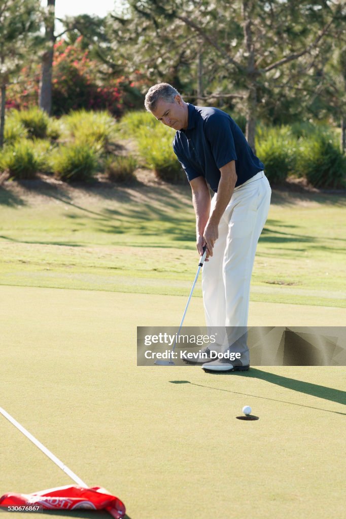 Caucasian man putting on golf course