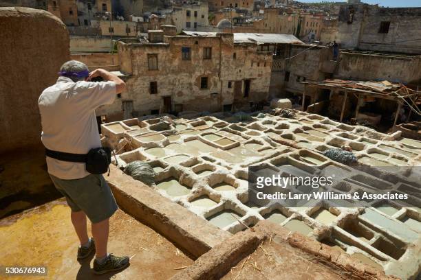 man photographing dilapidated ancient ruins in cityscape, medina, fes, morocco - fes morocco stock pictures, royalty-free photos & images