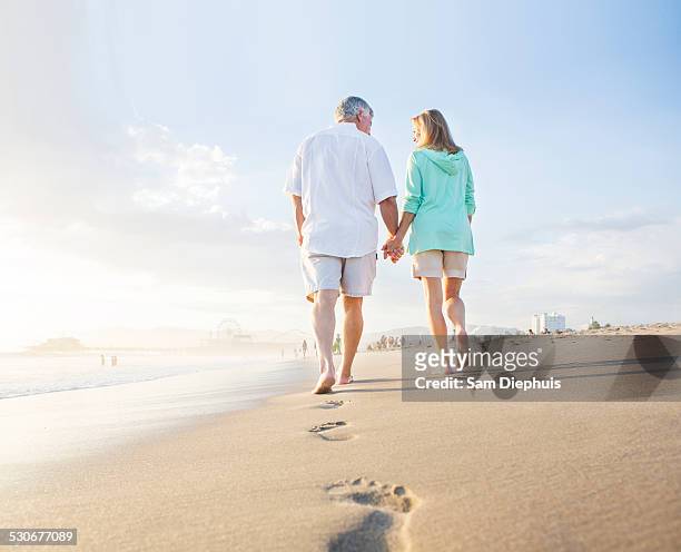 caucasian couple leaving footprints on beach - beach footprints stock pictures, royalty-free photos & images