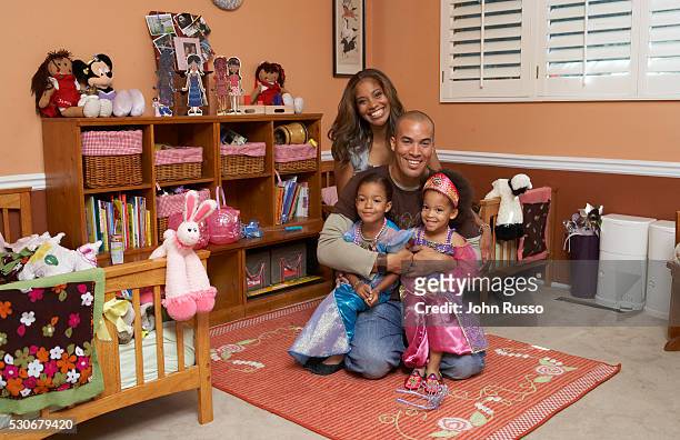 Coby and his wife Aviss pose in the children's room with twin daughters Serrae and Jaena.