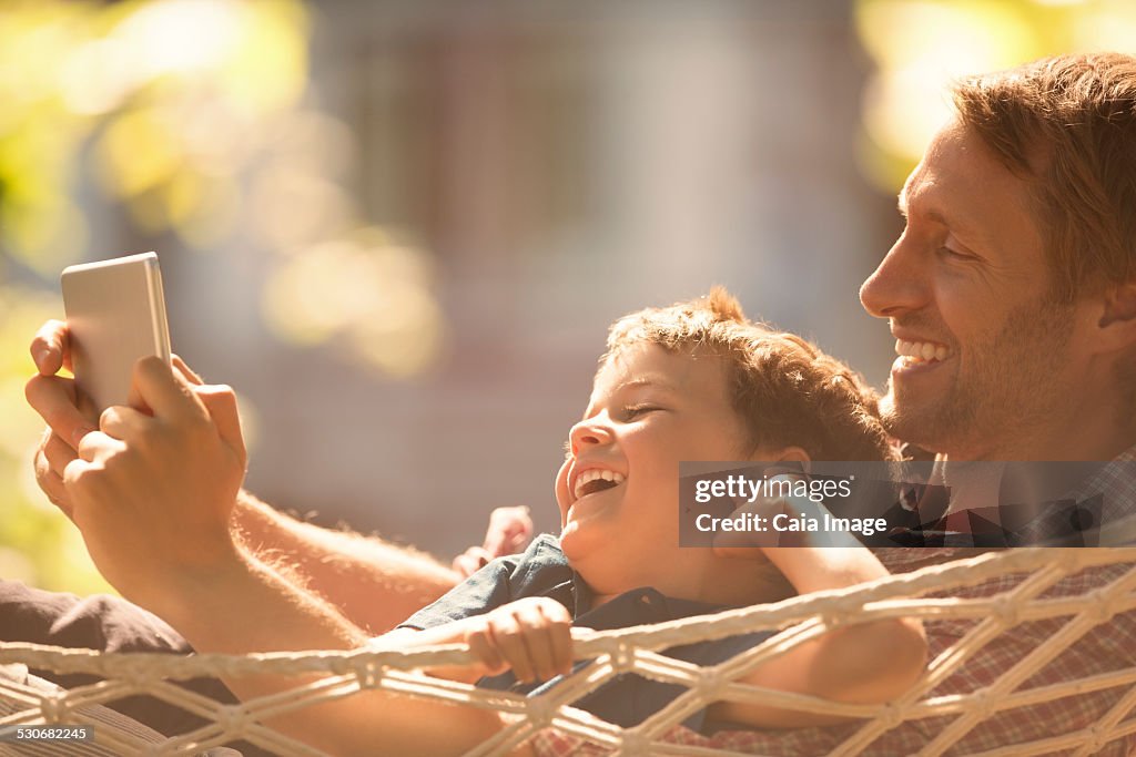 Father and son using digital tablet in hammock