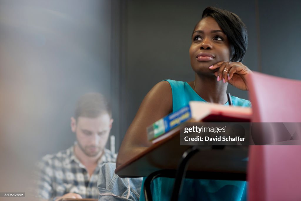 University student sitting at desk with hand on chin