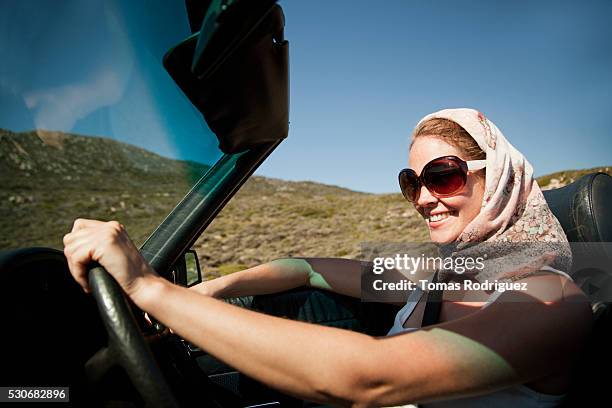 young woman in headscarf and sunglasses driving open car - open country ストックフォトと画像