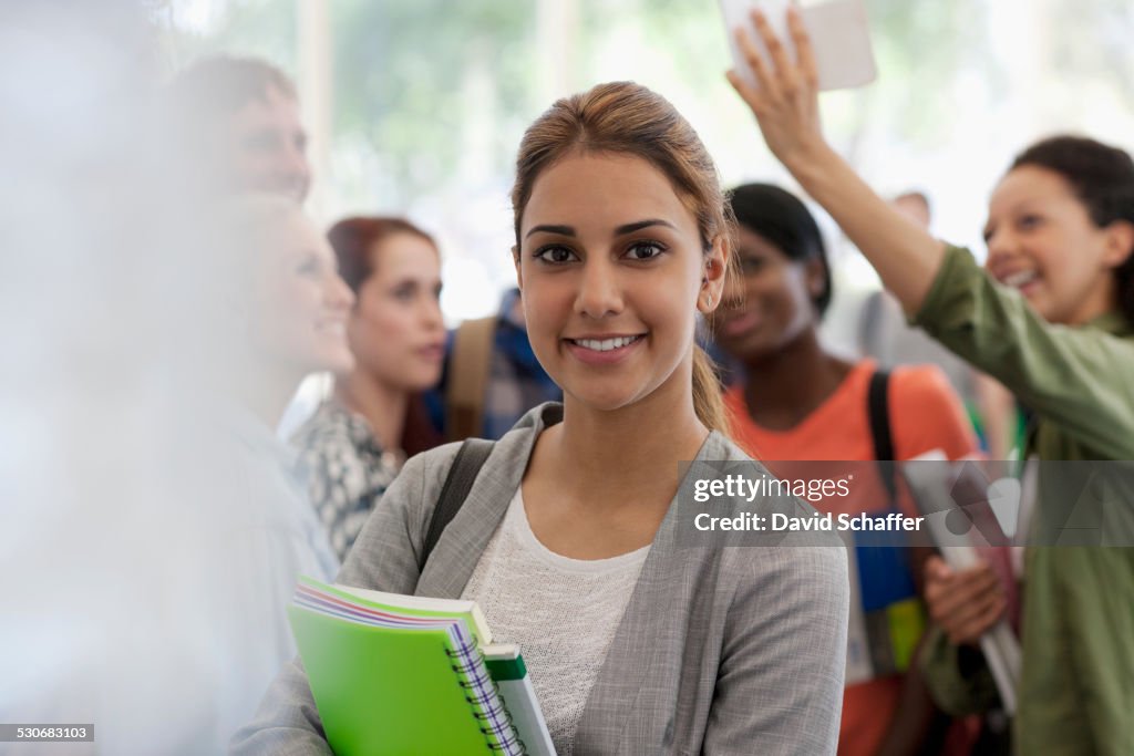 Smiling female student holding books during break