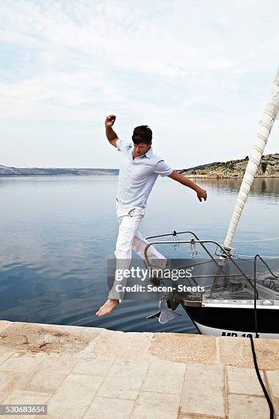 croatia, young man jumping onto pier - barefoot landing stock pictures, royalty-free photos & images