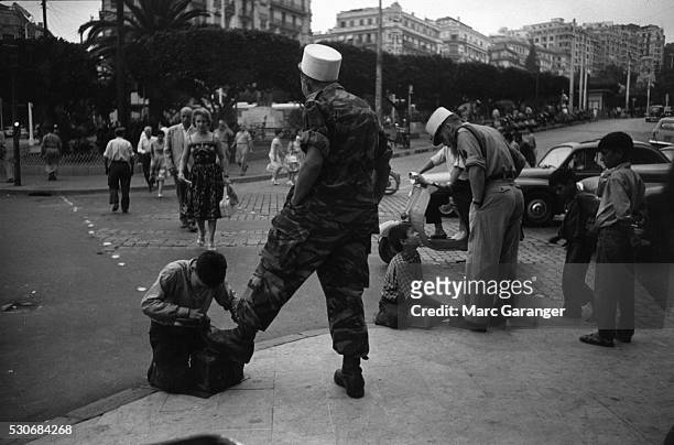 Algerian Boys Clean Boots of Colonial Paratroopers
