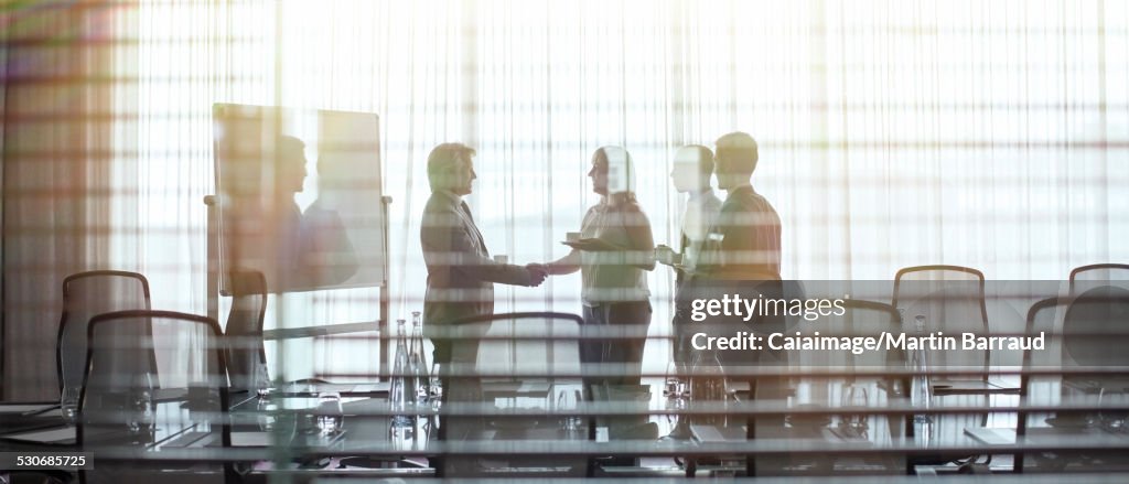 Business people standing in conference room shaking hands