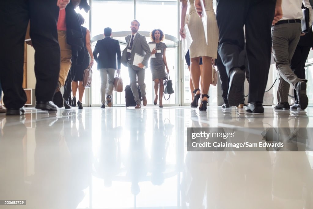 Geschäftsleute eilen durch bürohalle, reflexionen auf fliesenbedecktem Boden